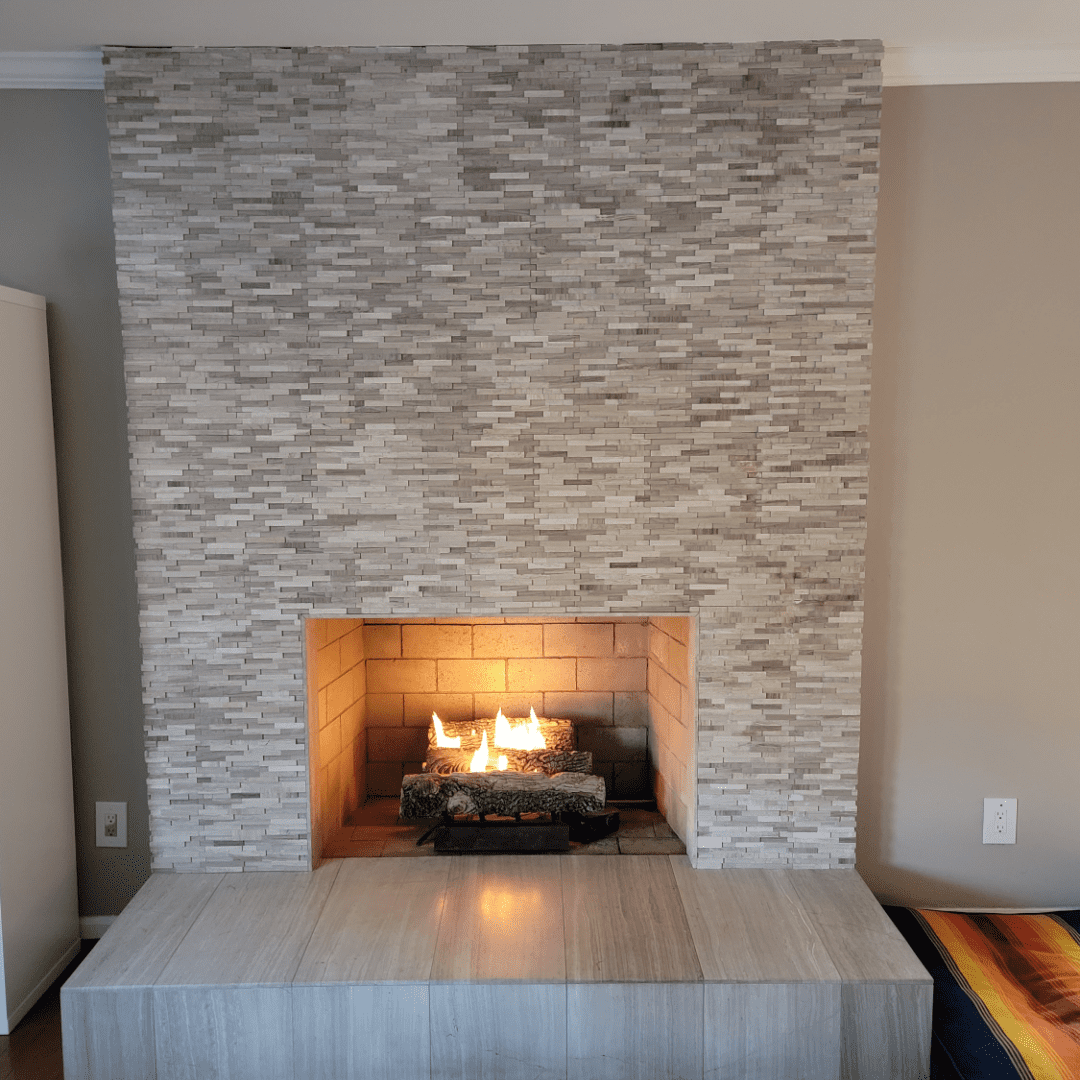 gas log set burning in a fireplace that has custom stone work from hearth to ceiling