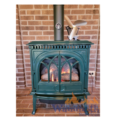 A green wood burning stove with a brick wall in the background.