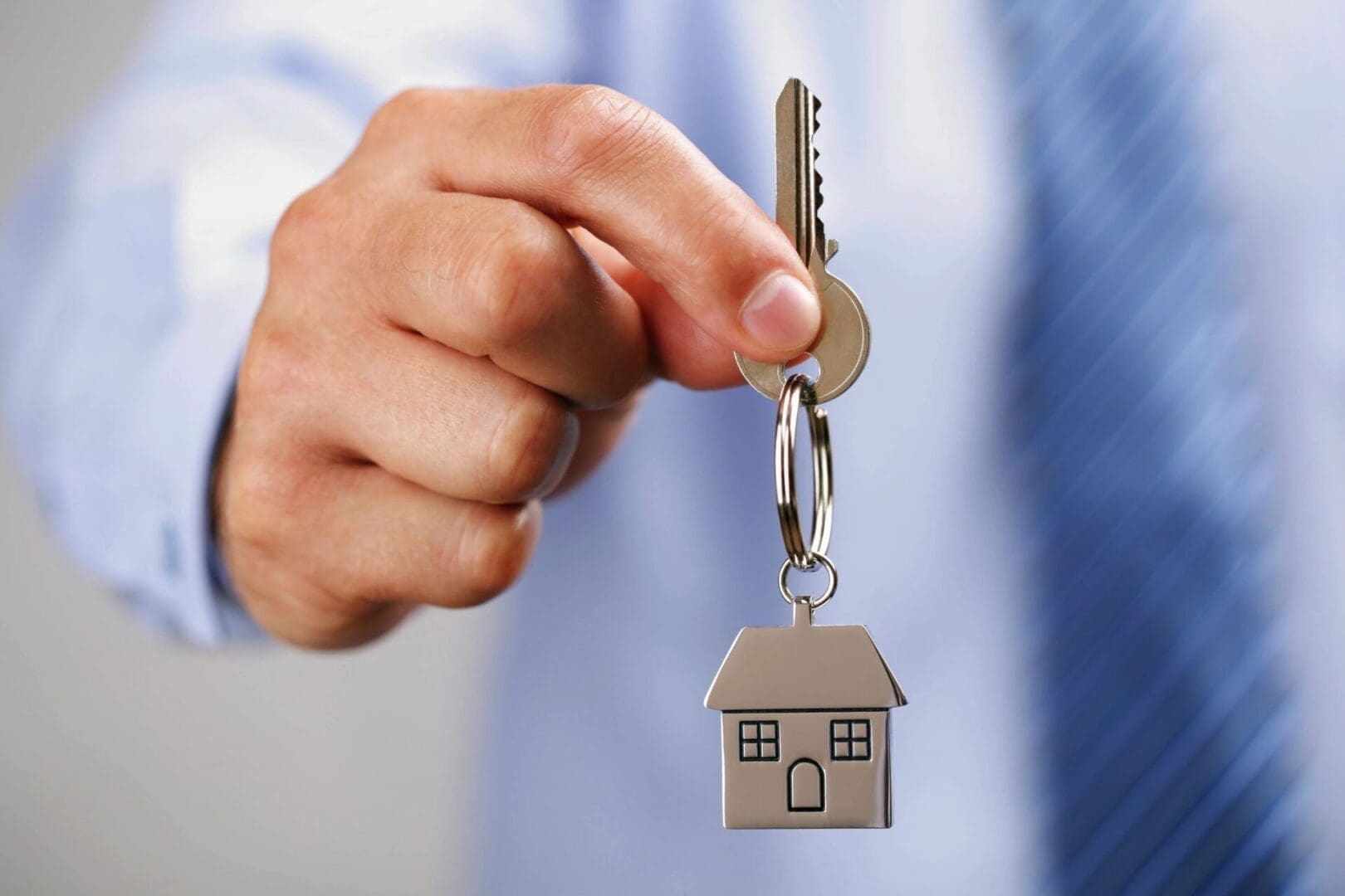 hand holding a key with a house keychain
